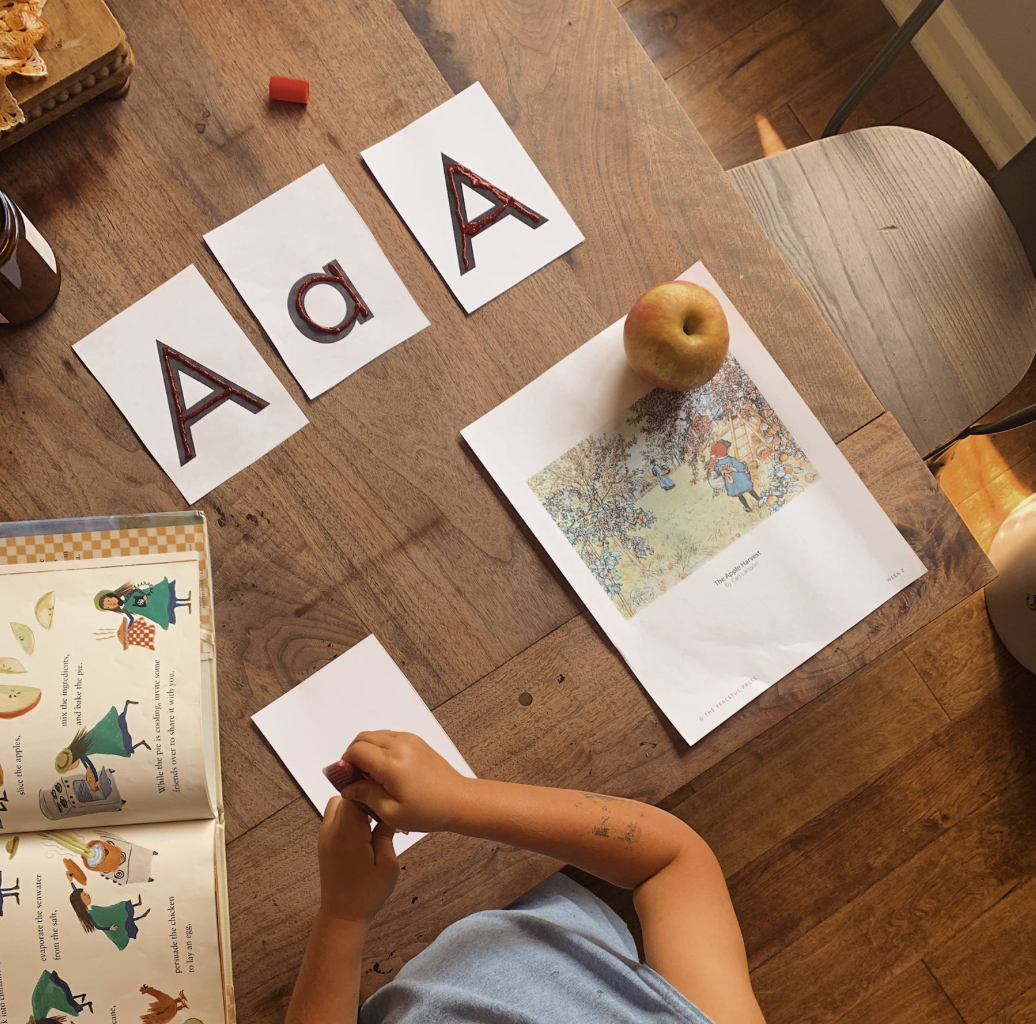Child learning letters with A and a on the table, showcasing a hands-on approach in Best Preschool Curriculum for Homeschool.