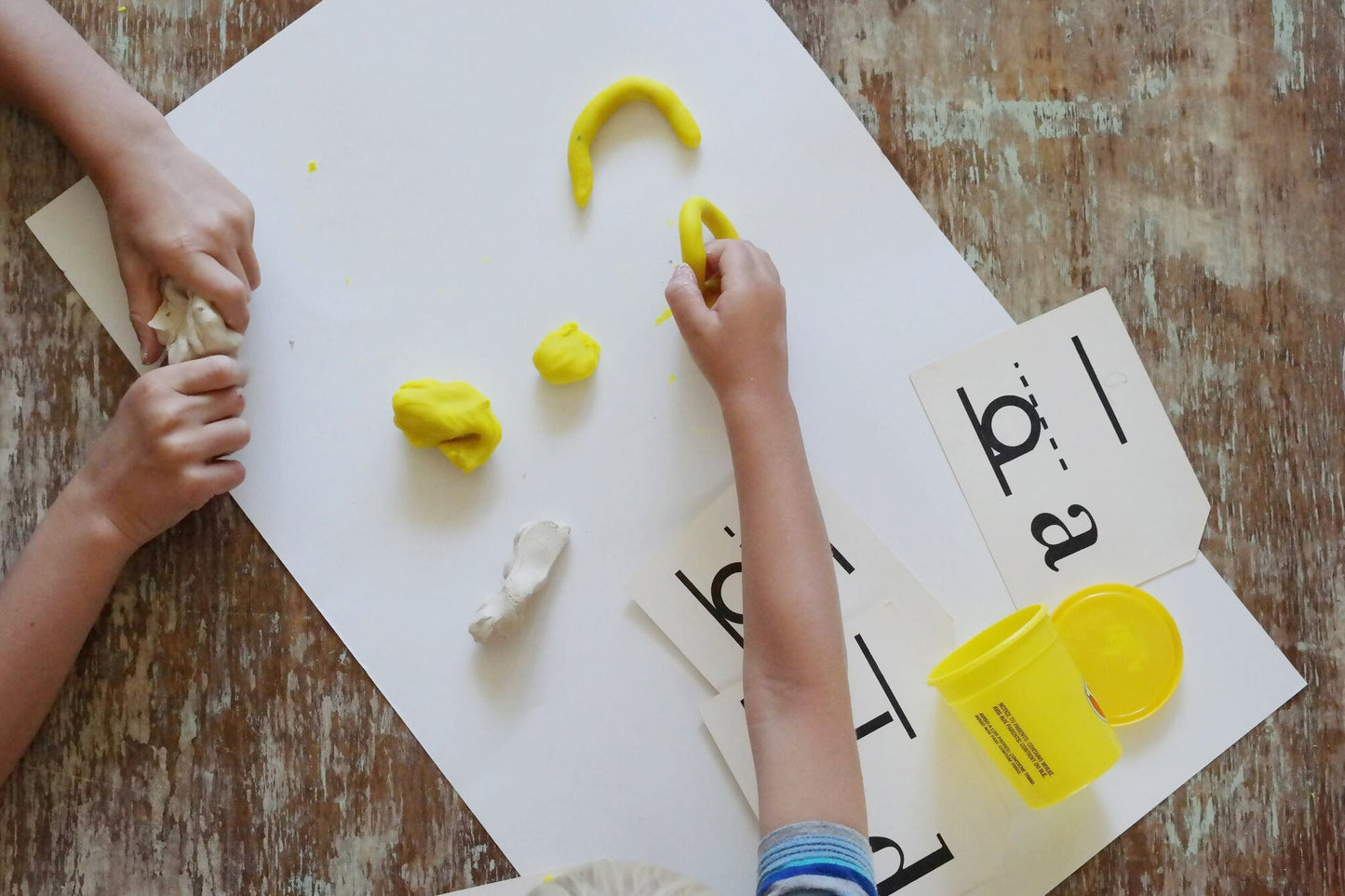 Homeschool preschoolers making letters out of play dough.