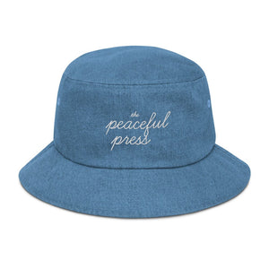 The Peaceful Press on a light denim bucket hat.