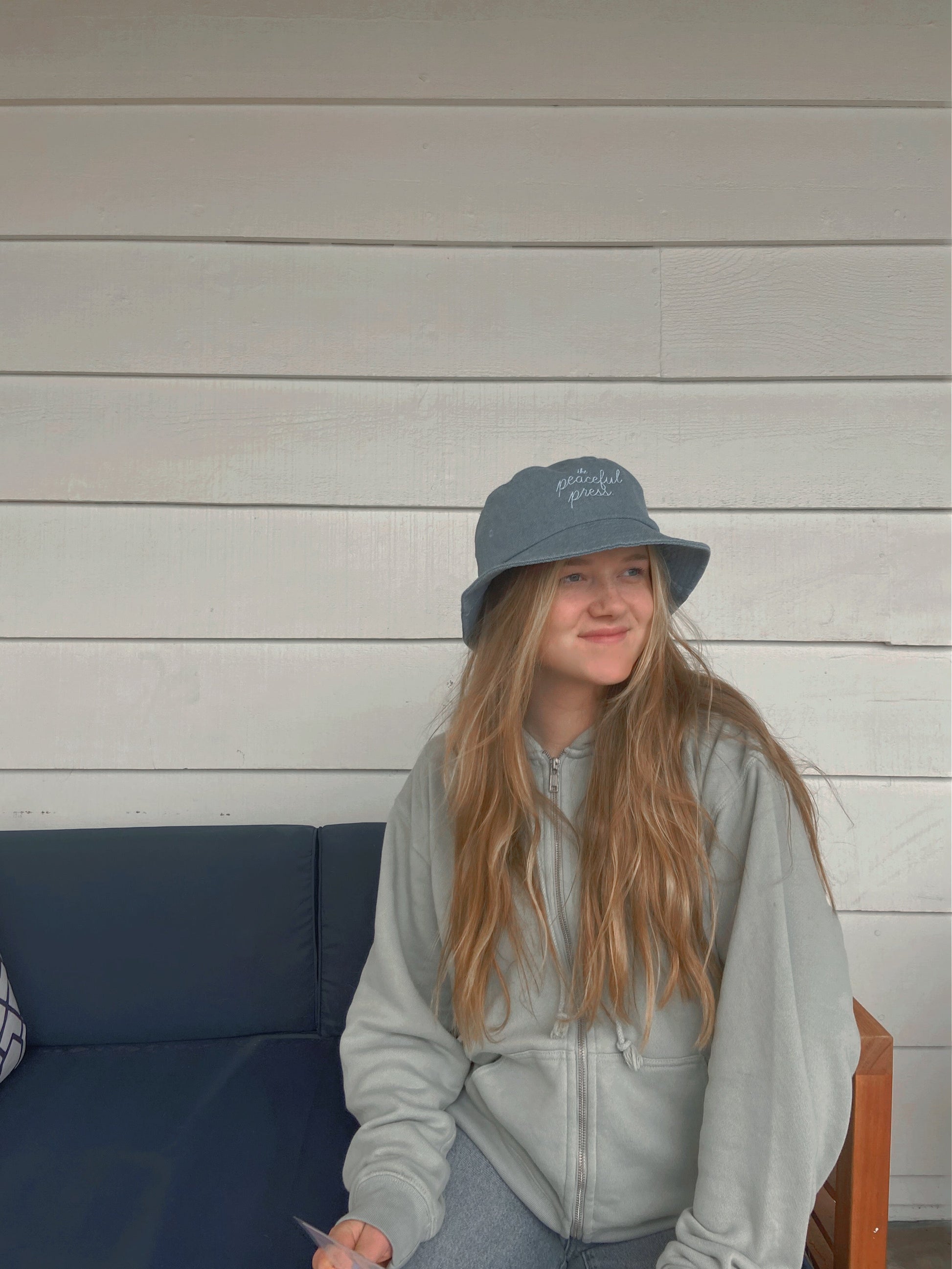 A homeschooler wearing The Peaceful Press on a light denim bucket hat.